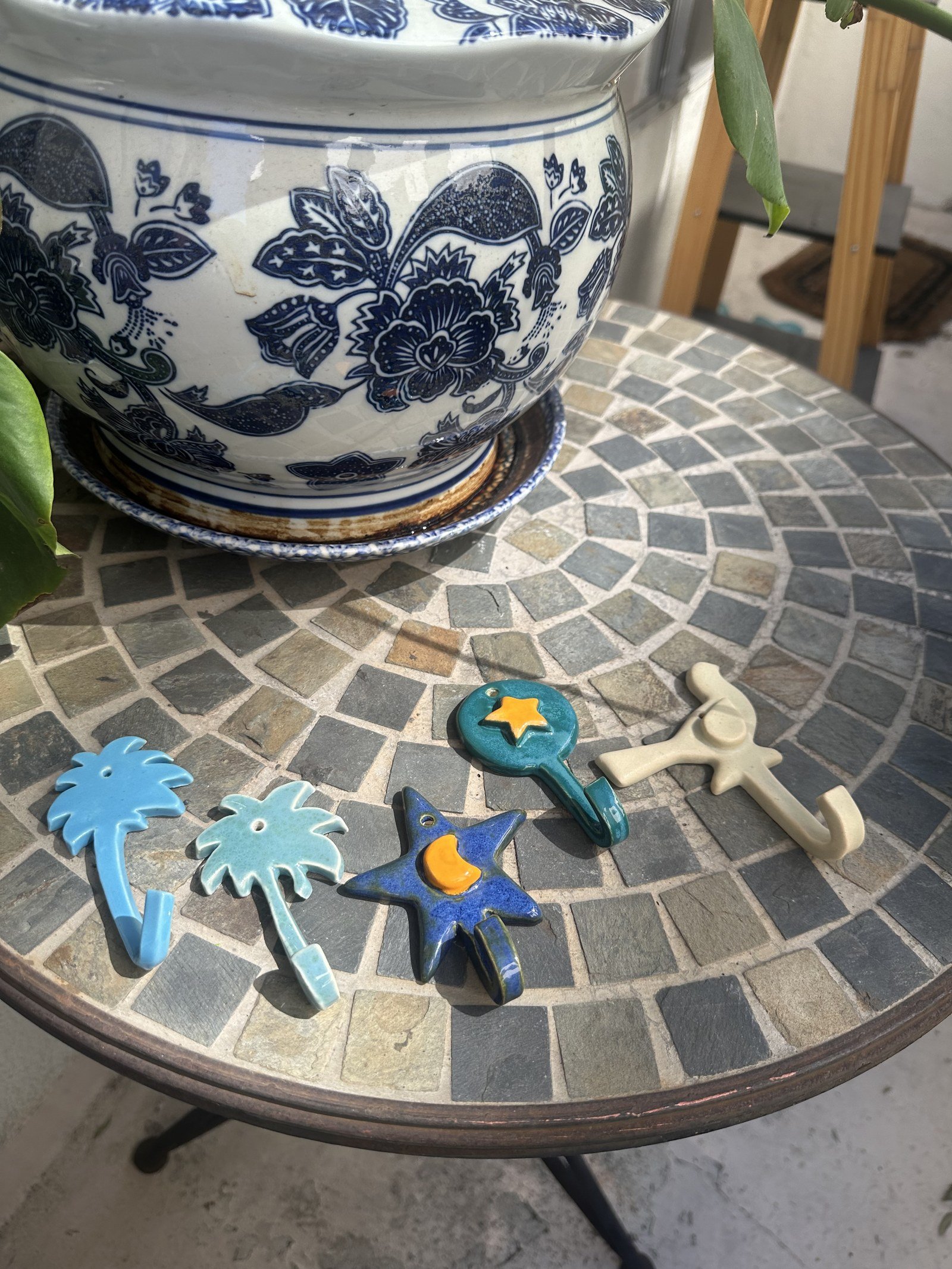 Small ceramic charm figurines arranged on a mosaic tile table outdoors