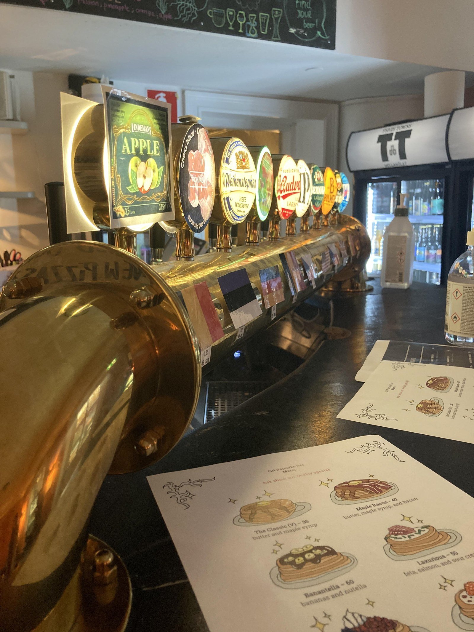 Printed pancake bar menus on a bar counter with beer taps in the background